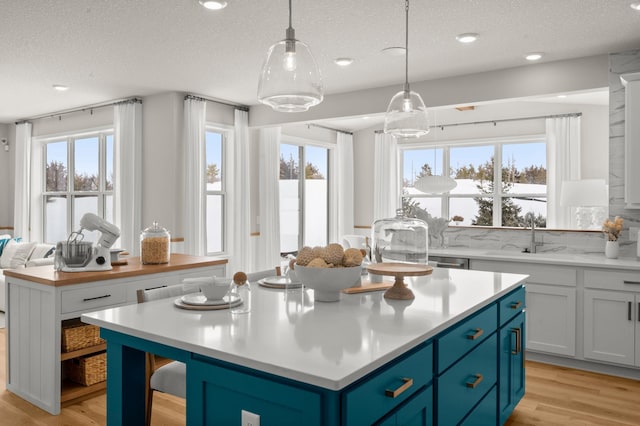 kitchen featuring decorative light fixtures, a center island, a textured ceiling, and blue cabinets