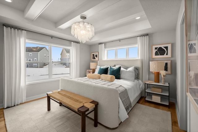 bedroom with a notable chandelier, beam ceiling, light hardwood / wood-style flooring, and multiple windows