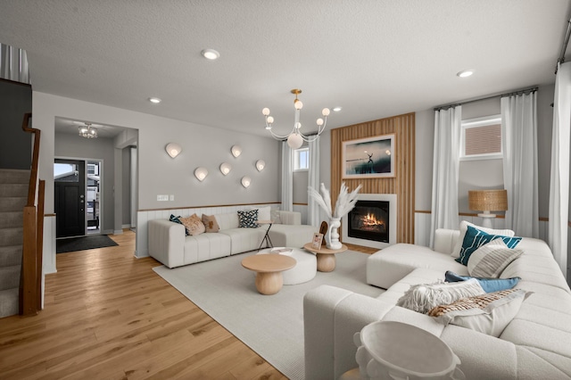 living room featuring a textured ceiling, light hardwood / wood-style flooring, and a notable chandelier