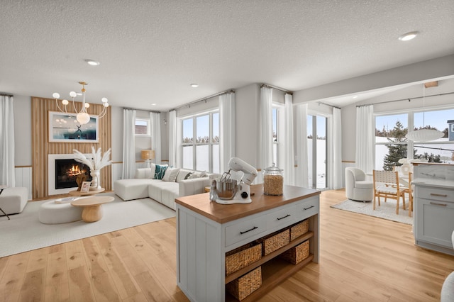 living room featuring light hardwood / wood-style floors, a textured ceiling, a notable chandelier, and plenty of natural light