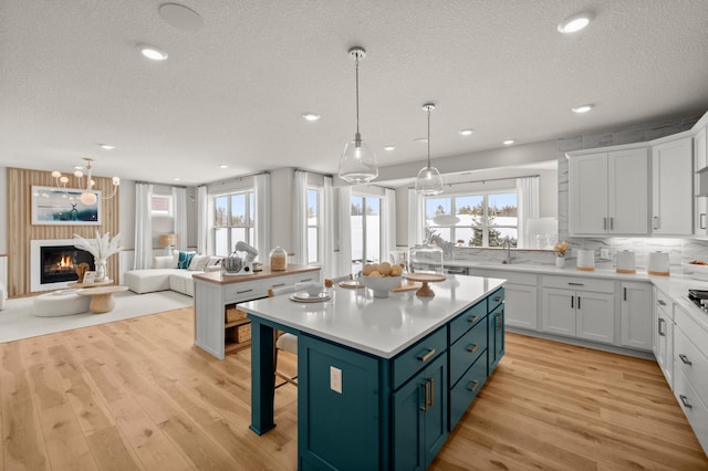 kitchen featuring pendant lighting, white cabinets, blue cabinetry, a wealth of natural light, and a kitchen island