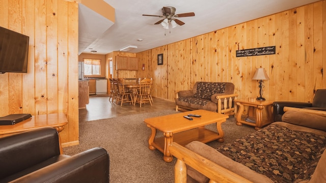 living room featuring ceiling fan, wooden walls, and carpet