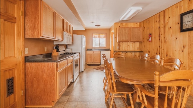 kitchen with sink, white appliances, and wood walls