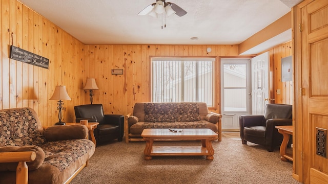 carpeted living room featuring ceiling fan and wooden walls