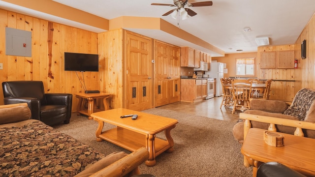 carpeted living room featuring ceiling fan, wood walls, and electric panel