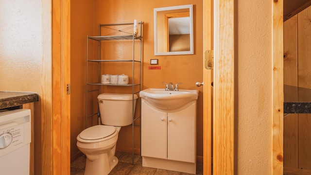 bathroom featuring vanity, washer / clothes dryer, and toilet