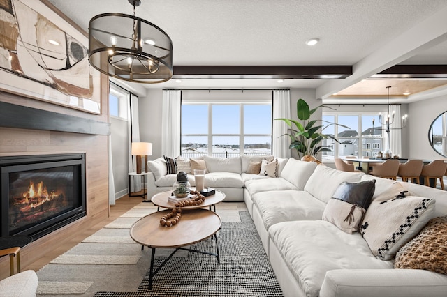 living room with a textured ceiling, an inviting chandelier, light hardwood / wood-style floors, and beam ceiling