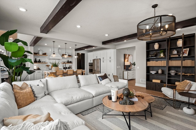 living room featuring hardwood / wood-style flooring, beamed ceiling, a textured ceiling, a chandelier, and sink