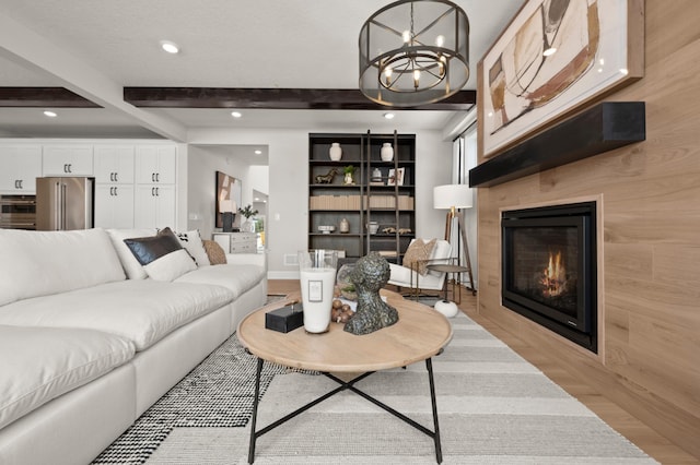 living room featuring light hardwood / wood-style floors, wooden walls, beamed ceiling, a notable chandelier, and built in shelves