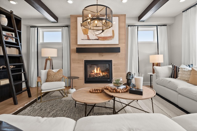 living room featuring a large fireplace, plenty of natural light, beamed ceiling, and a chandelier