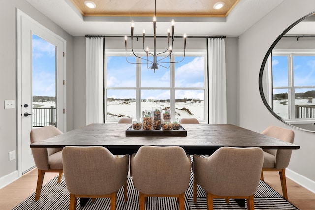 dining room with a chandelier, light hardwood / wood-style floors, and a tray ceiling