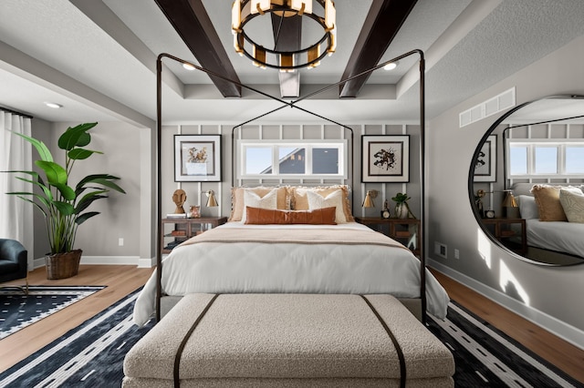 bedroom featuring an inviting chandelier, beam ceiling, and wood-type flooring