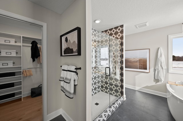 bathroom with a textured ceiling and shower with separate bathtub