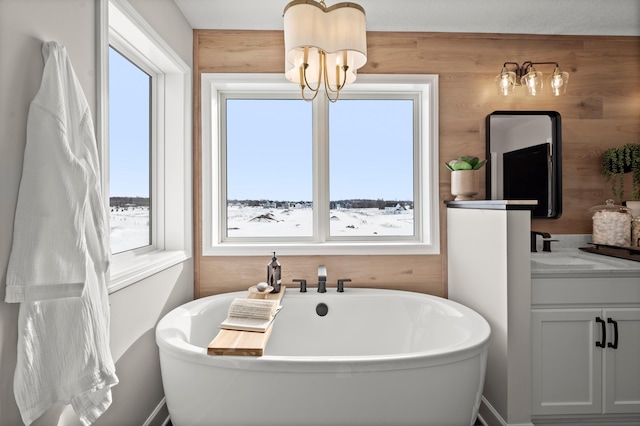 bathroom with a bathing tub, a wealth of natural light, wooden walls, and a notable chandelier