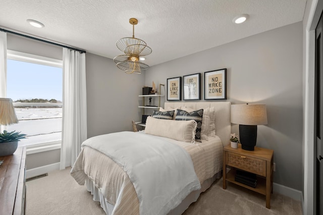 bedroom with light colored carpet and a textured ceiling