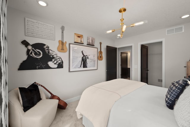 bedroom featuring light carpet, a spacious closet, a closet, a textured ceiling, and a chandelier