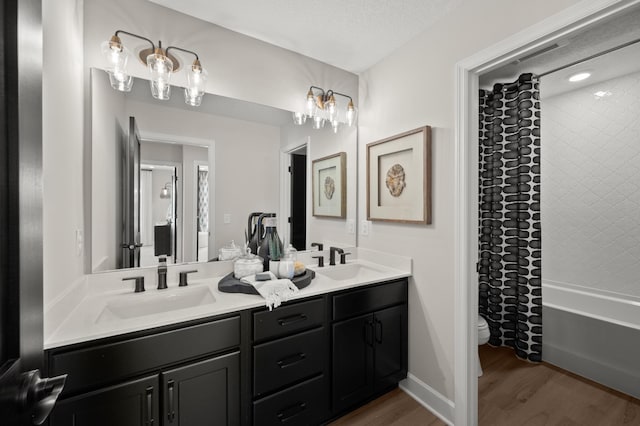 full bathroom featuring toilet, hardwood / wood-style floors, shower / tub combo with curtain, a textured ceiling, and vanity