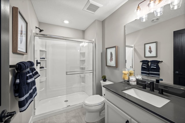 bathroom with a textured ceiling, toilet, a shower with door, and vanity