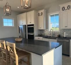 kitchen featuring appliances with stainless steel finishes, pendant lighting, white cabinetry, and a kitchen island