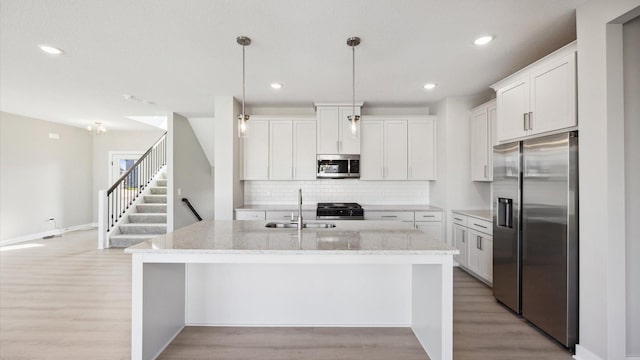 kitchen with white cabinets, an island with sink, and stainless steel appliances