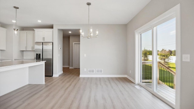 kitchen with pendant lighting, white cabinets, an inviting chandelier, tasteful backsplash, and stainless steel fridge