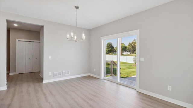 unfurnished dining area featuring light hardwood / wood-style floors and an inviting chandelier