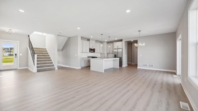 unfurnished living room featuring light wood-type flooring and a chandelier