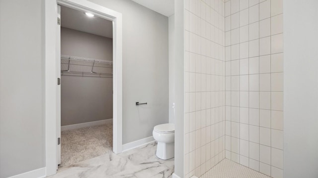 bathroom with toilet and a tile shower