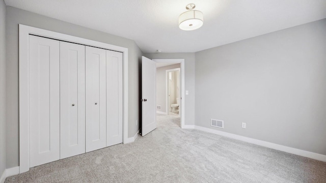 unfurnished bedroom with light colored carpet and a closet