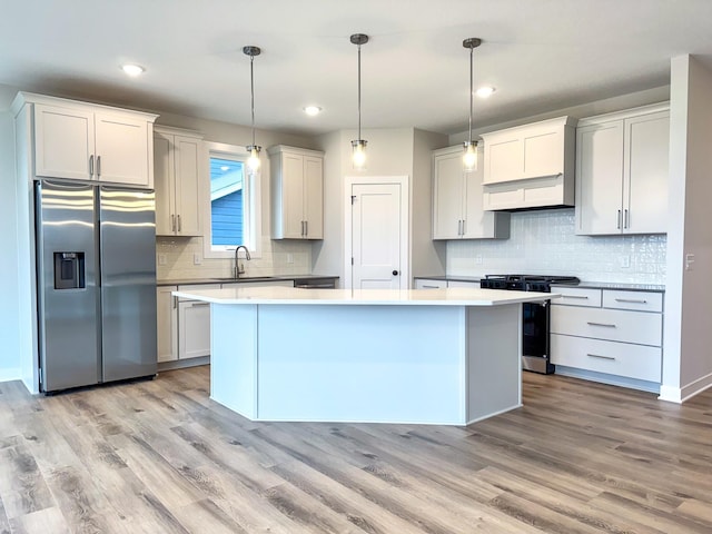 kitchen with pendant lighting, white cabinetry, light hardwood / wood-style flooring, and appliances with stainless steel finishes