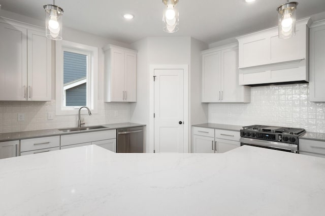 kitchen with sink, white cabinetry, hanging light fixtures, backsplash, and stainless steel appliances