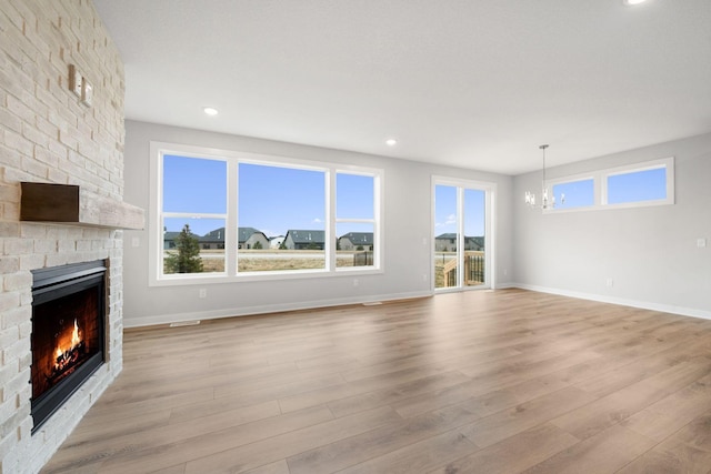 unfurnished living room with a fireplace, light hardwood / wood-style flooring, and a notable chandelier