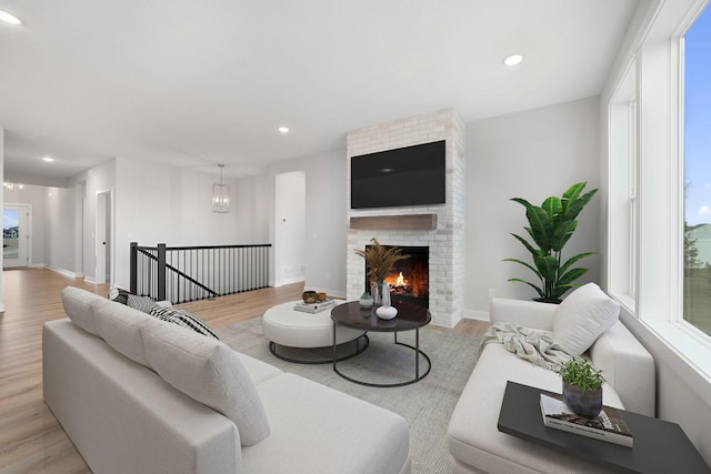 living room featuring a notable chandelier, a fireplace, and light hardwood / wood-style floors