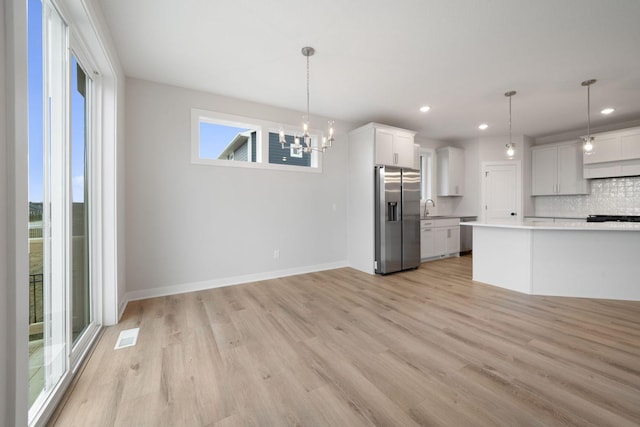 kitchen featuring stainless steel fridge with ice dispenser, backsplash, hanging light fixtures, and white cabinets