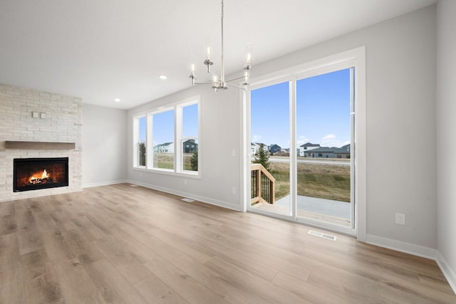 unfurnished living room with a fireplace, light hardwood / wood-style floors, and a chandelier