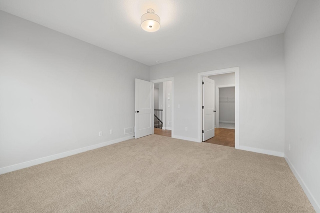 unfurnished bedroom with a spacious closet, carpet floors, and a closet