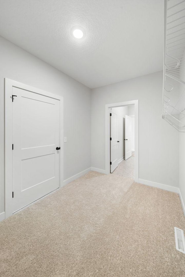 unfurnished room featuring light colored carpet and a textured ceiling