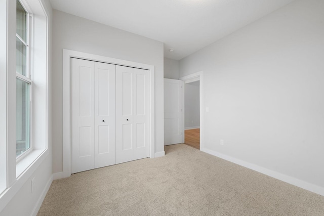 unfurnished bedroom featuring light carpet and a closet