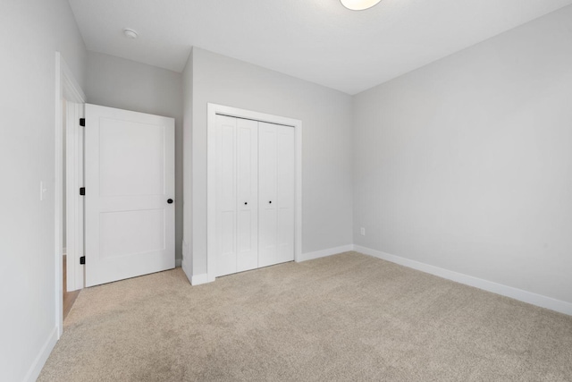 unfurnished bedroom featuring light colored carpet and a closet