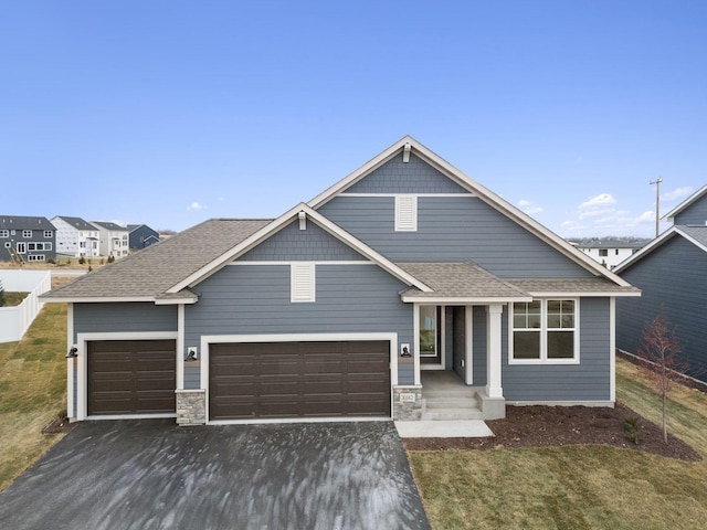 10142 Arrowwood Trl, Woodbury, MN 55129 - view of front of home with fence, asphalt driveway, an attached garage, a shingled roof, and stone siding