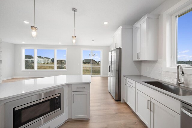 10142 Arrowwood Trl, Woodbury, MN 55129 - kitchen featuring appliances with stainless steel finishes, a sink, healthy amount of natural light, hanging light fixtures, and recessed lighting