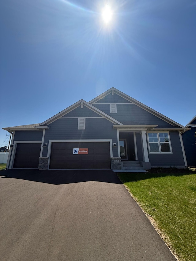 10142 Arrowwood Trl, Woodbury, MN 55129 - view of front facade featuring a front yard, asphalt driveway, an attached garage, and stone siding