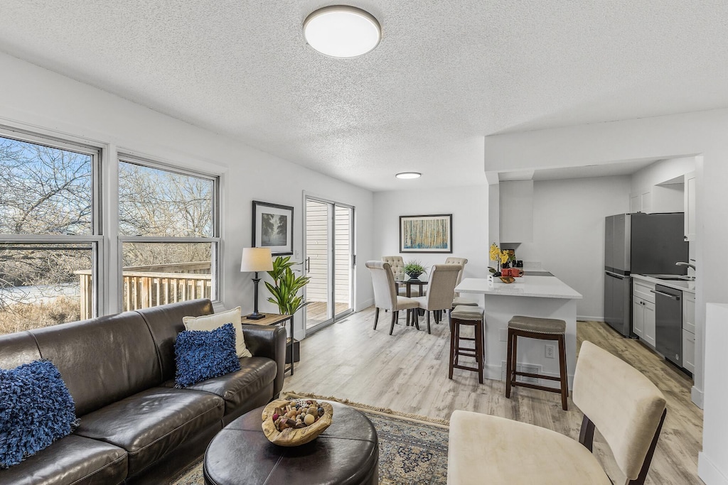 living room with a textured ceiling and light wood-type flooring