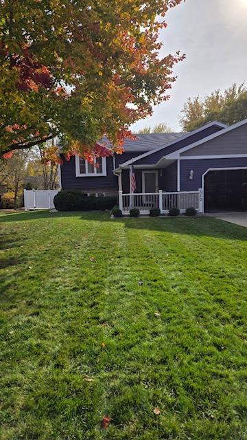 view of front of property featuring a porch, a front lawn, and a garage