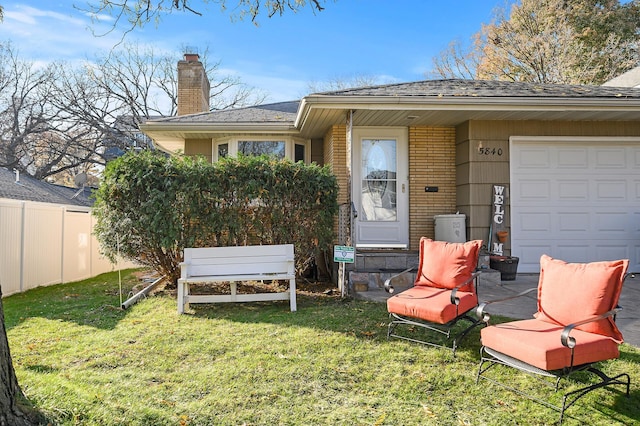 rear view of property with a garage and a lawn