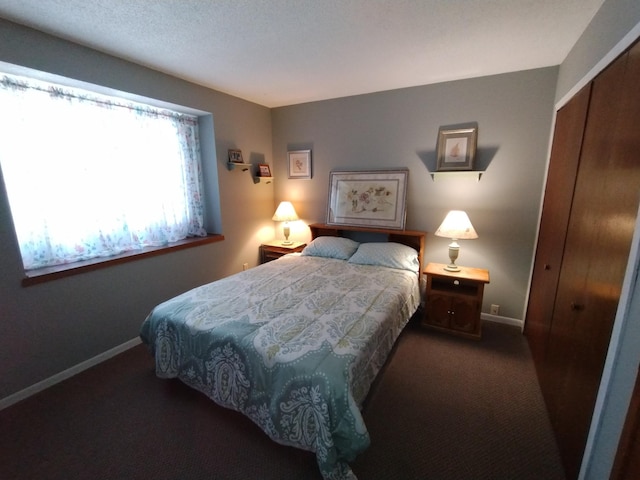 bedroom with baseboards, dark colored carpet, and a closet