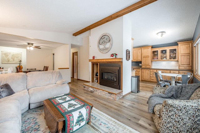 living room featuring light wood-type flooring, ceiling fan, and vaulted ceiling with beams