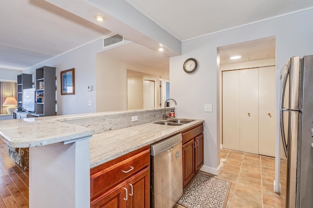 kitchen with a kitchen bar, light stone countertops, sink, and appliances with stainless steel finishes