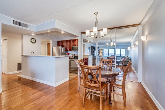 dining room with light wood-type flooring, an inviting chandelier, and sink