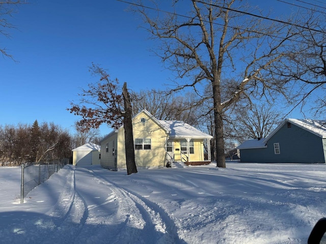 view of snow covered exterior featuring a garage and an outdoor structure